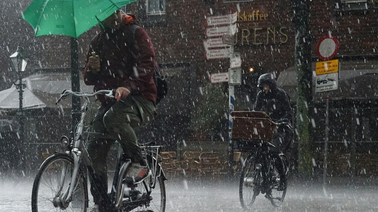 Two bicyclists riding single-file in a downpour