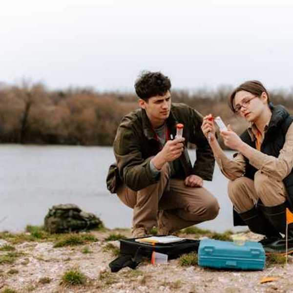 Two biologists testing water by the side of a river