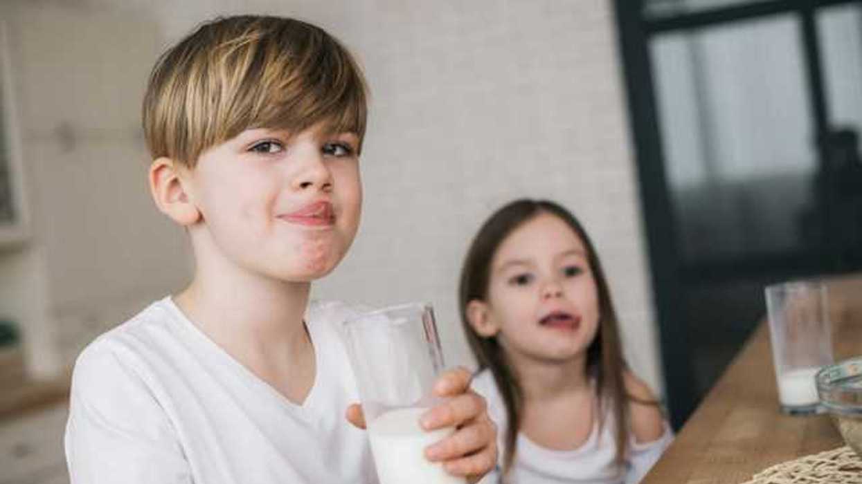 Two children drinking glasses of milk