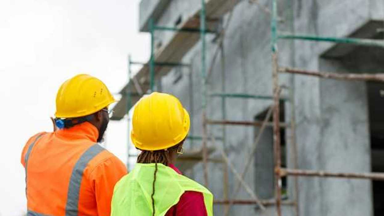 Two construction workers looking up at scaffolding on a new build
