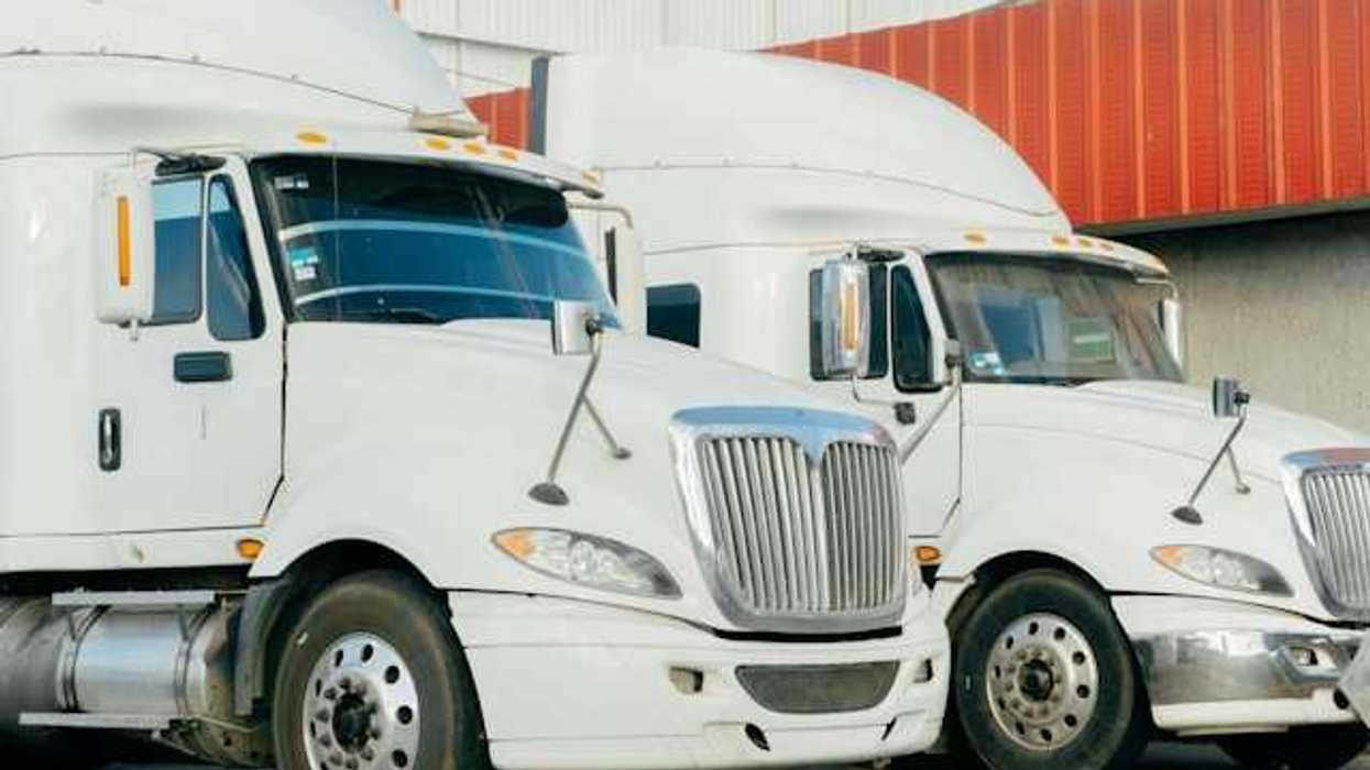 Two diesel 18-wheeler trucks sitting in a parking lot