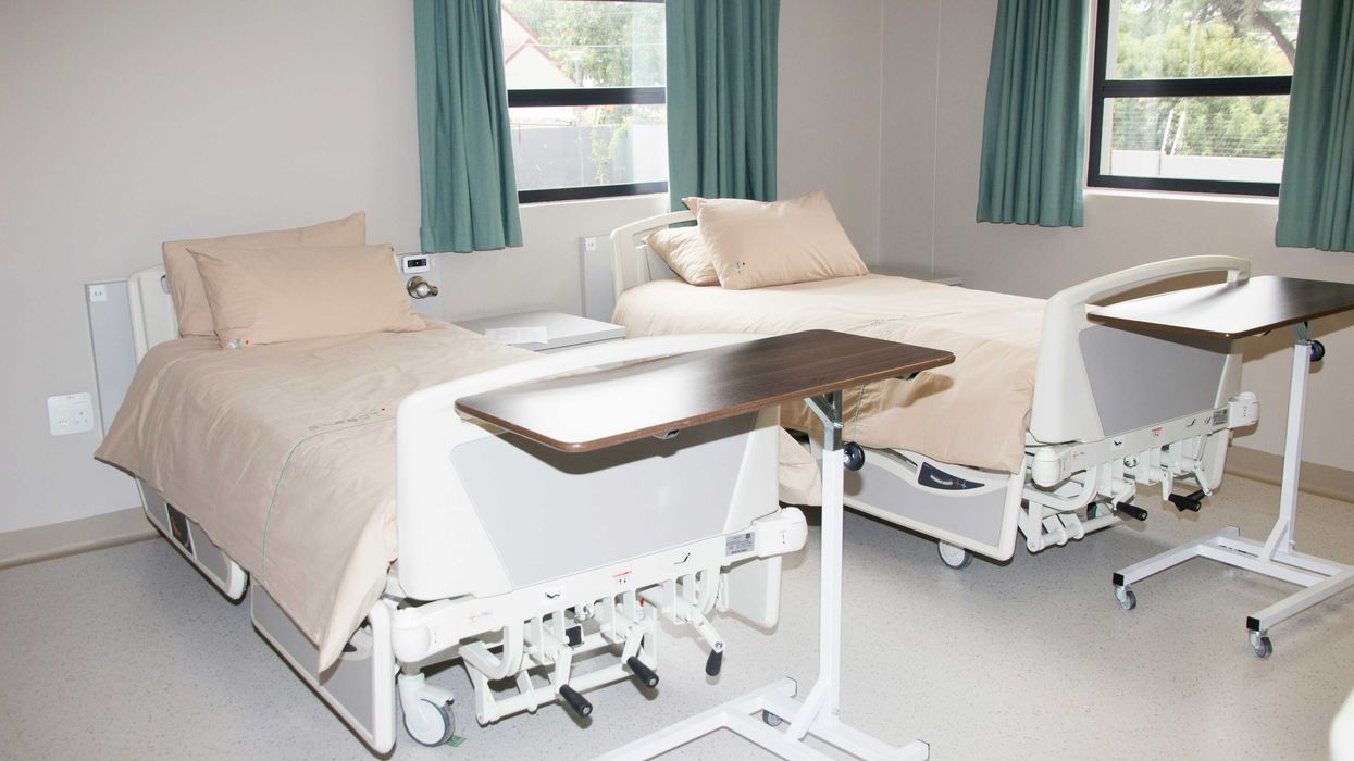 Two empty hospital beds near windows