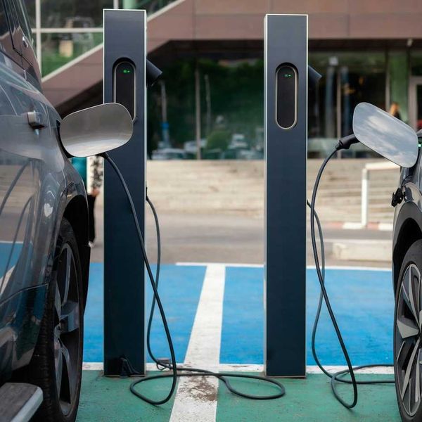 two EVs, side by side, being recharged at charging stations