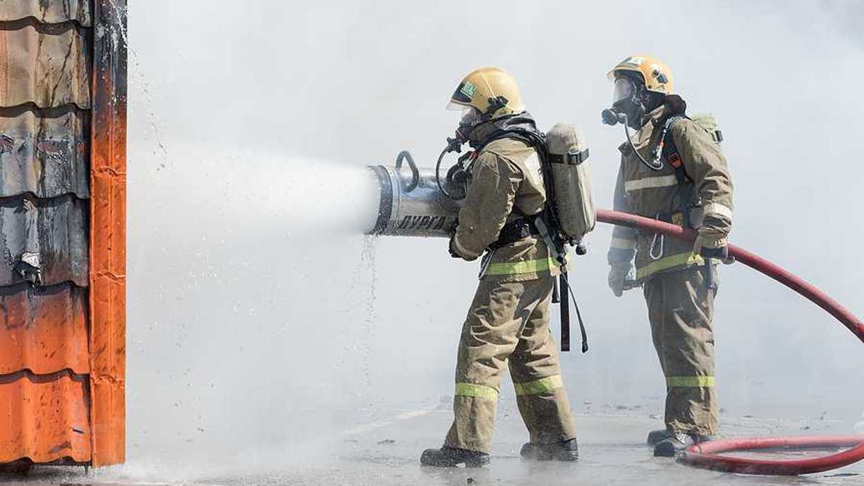 Two firefighters spraying foam at a fire