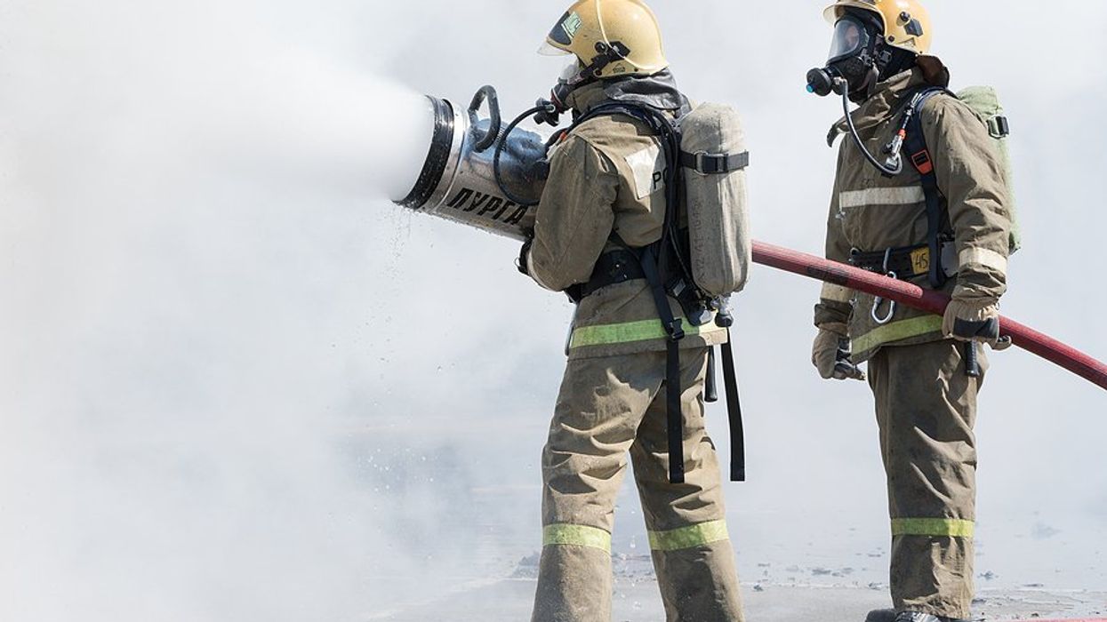 Two firefighters spraying foam on a fire.