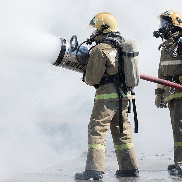 Two firefighters spraying foam on a fire.