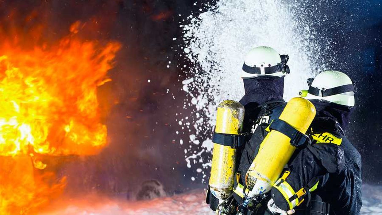 Two firefighters spraying foam toward flames