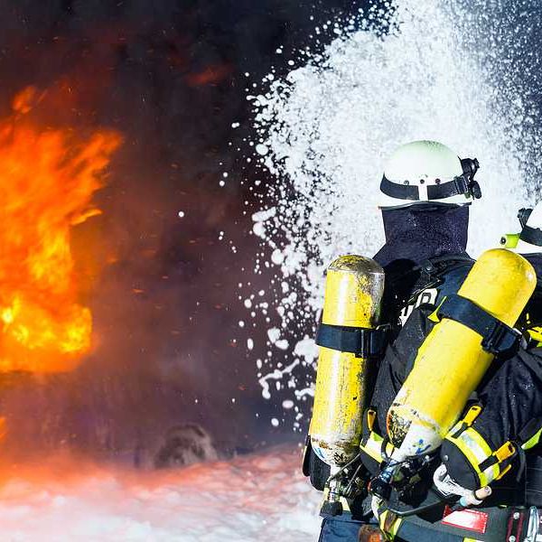 Two firefighters spraying foam toward flames