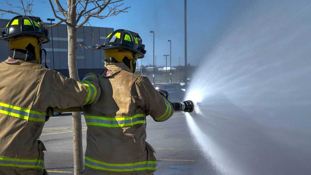 Two firemen spraying foam in a parking lot