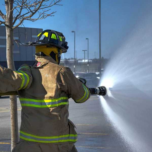 Two firemen spraying foam in a parking lot