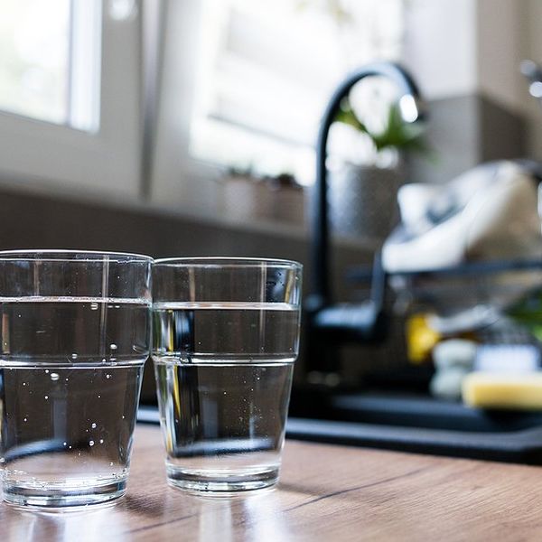 Two glasses of water sitting on the counter next to the kitchen sink