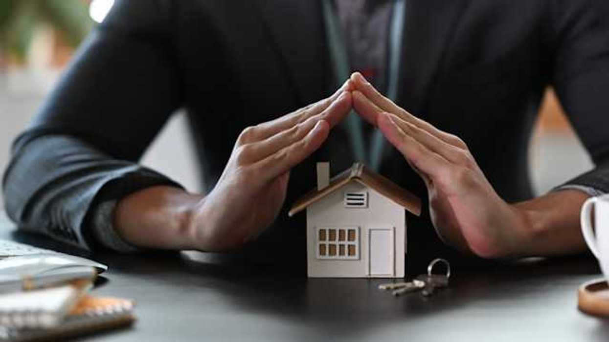Two hands cupped over a model of a house