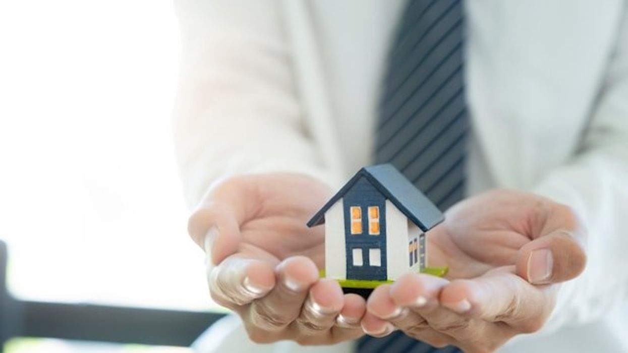 Two hands holding a model of a house in their hands