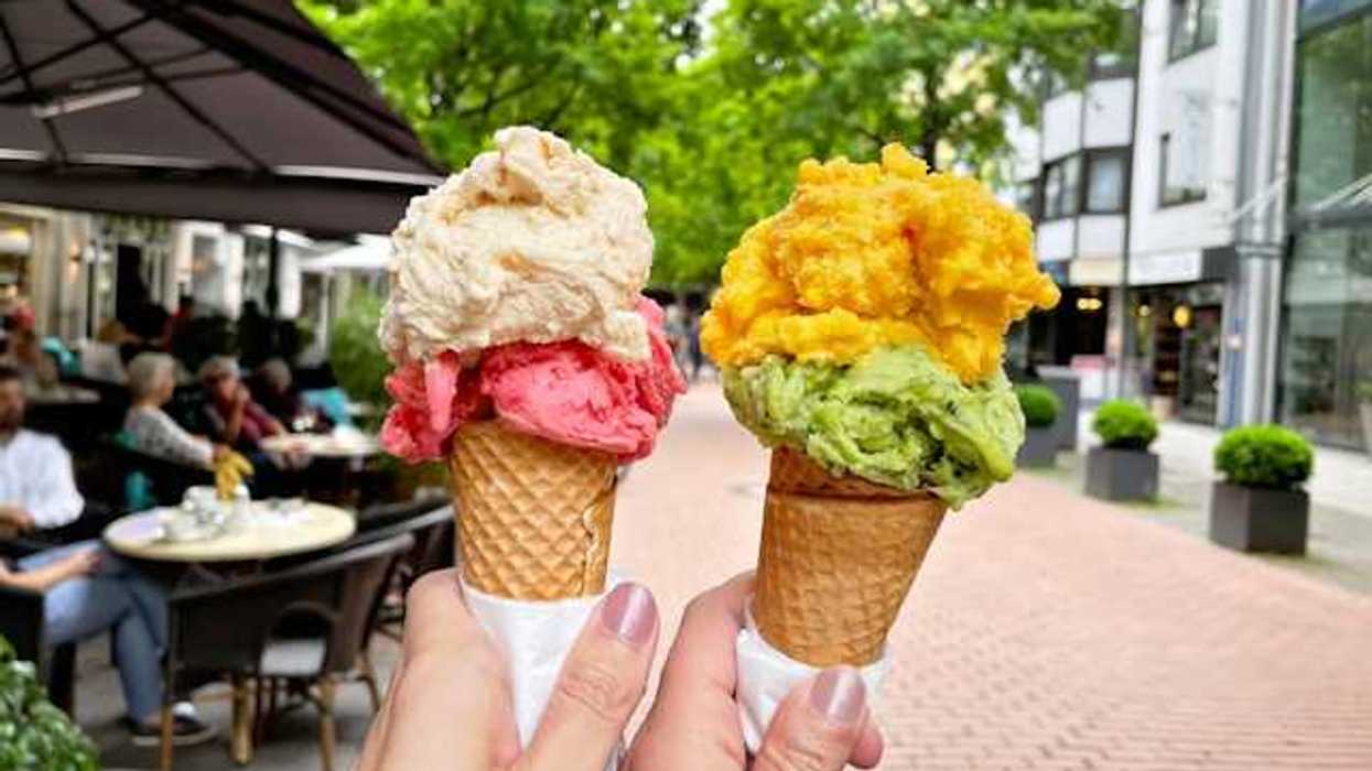 Two hands holding ice cream cones in a city street