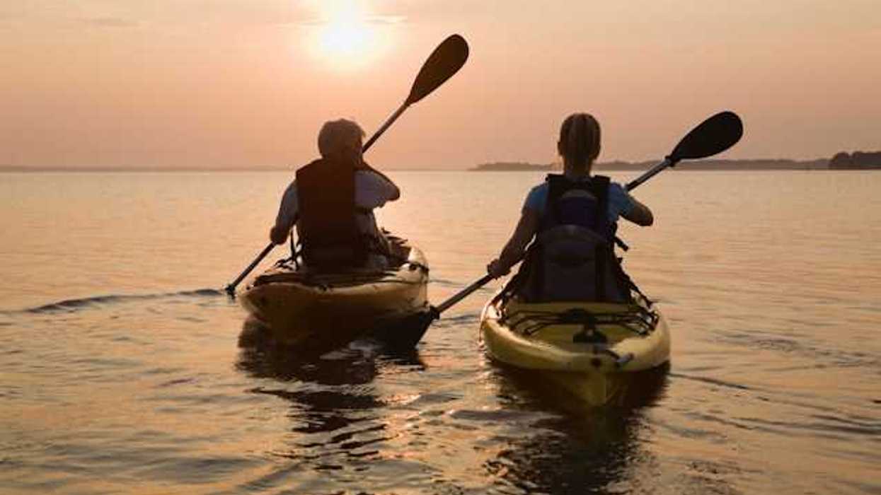Two kayakers paddling into the setting sun