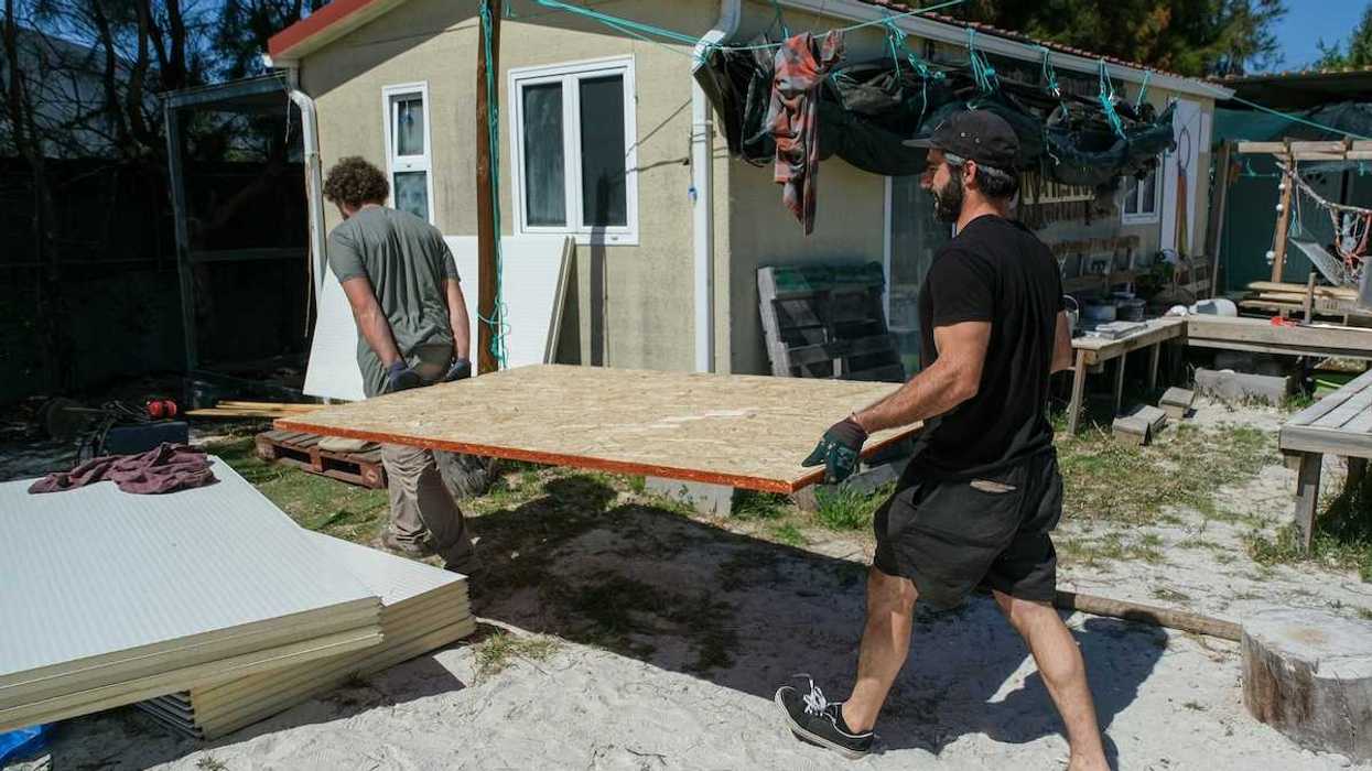 Two men carrying sheets of chipboard for structural repair or construction