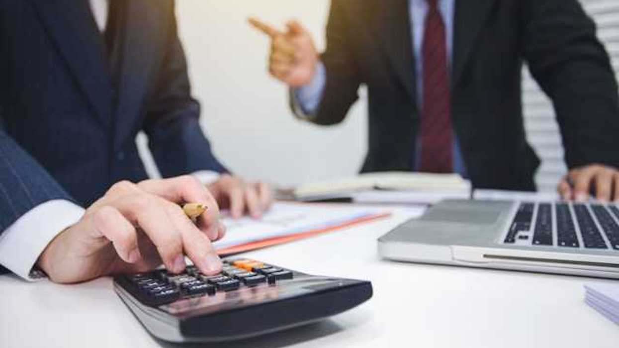 Two men in suits tallying numbers on a calculator