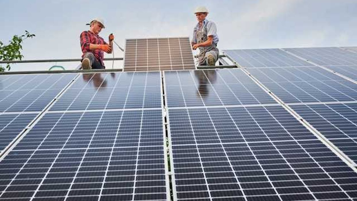 Two men installing solar panels on a roof