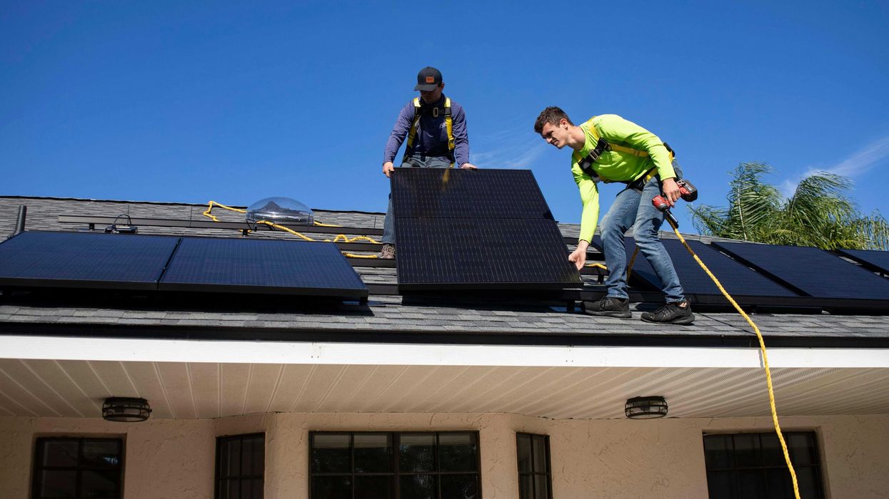 Two men installing solar panels on a roof