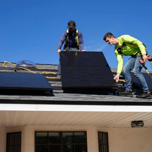 Two men installing solar panels on a roof