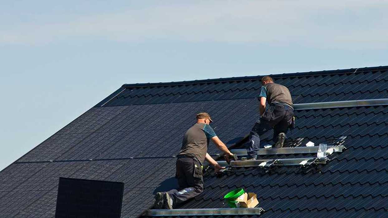 Two men installing solar panels on a roof