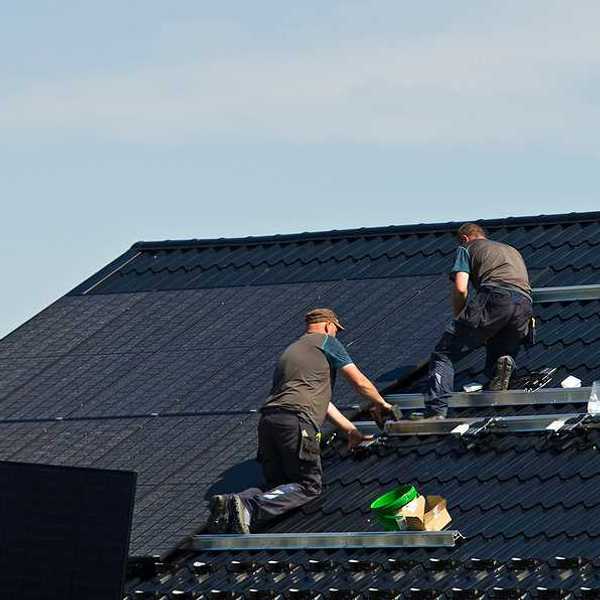 Two men installing solar panels on a roof