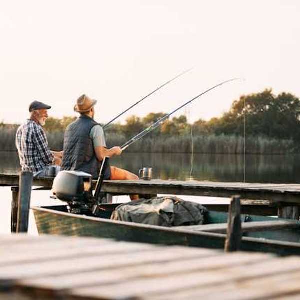Two men sitting on a dock fishing on a lake