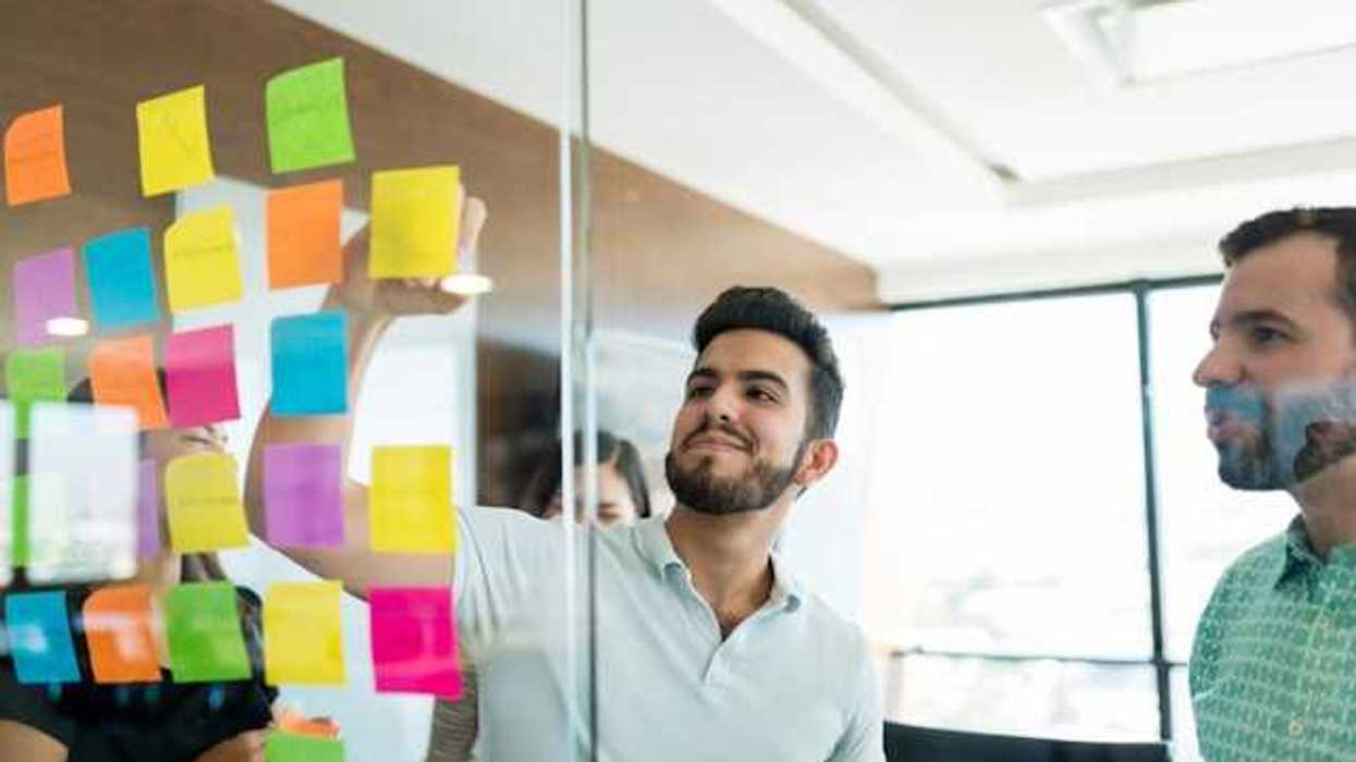 Two men standing in front of a glass wall with post-its on it