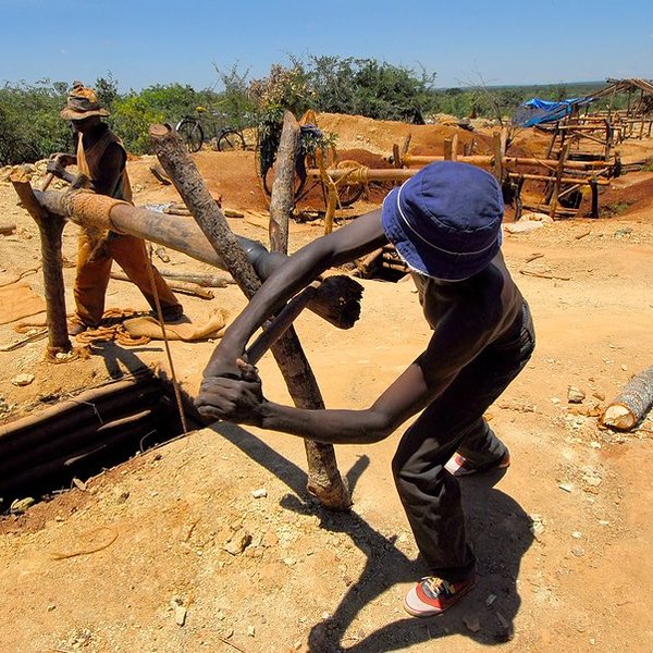 two men turning a wooden post with a rope attached to it going underground