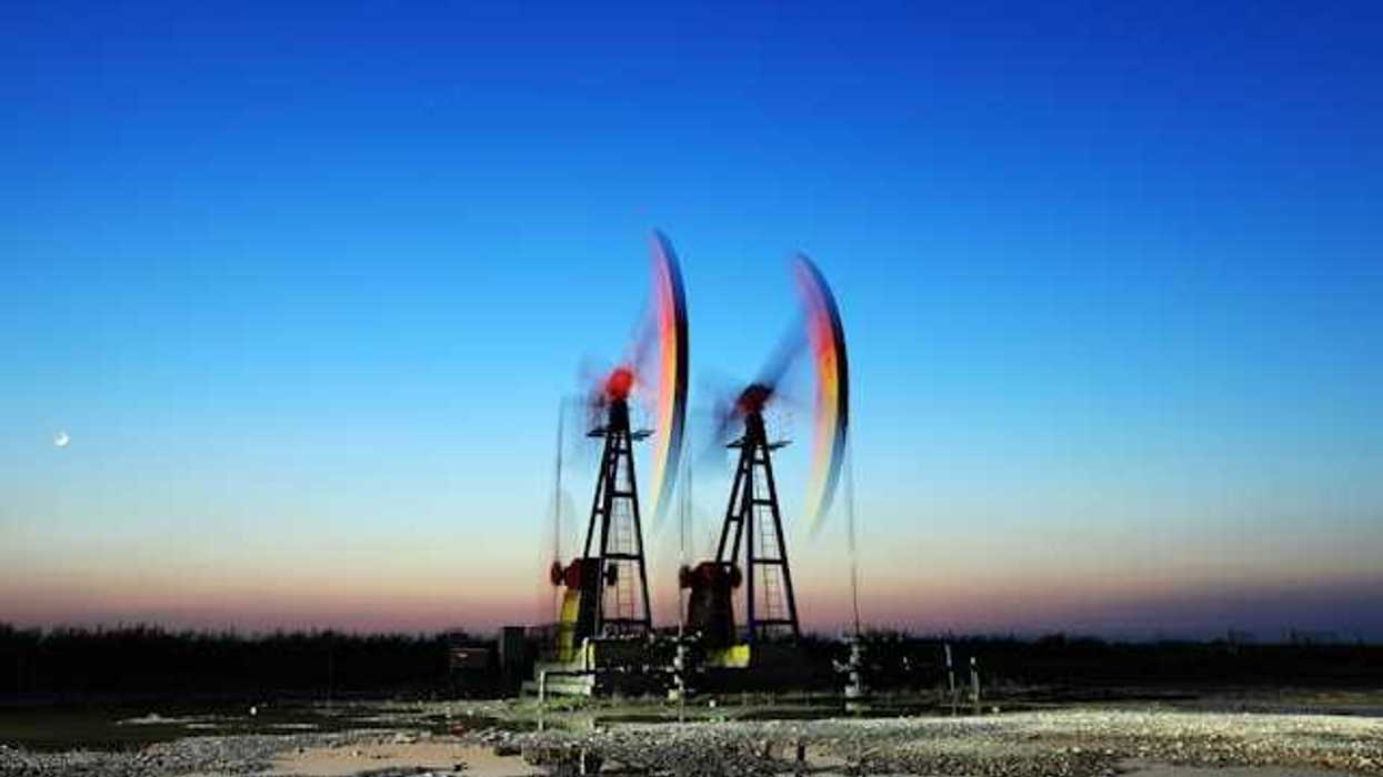 Two oil pump jacks against the setting sun