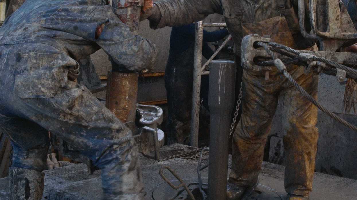 Two oilfield workers working on drilling equipment