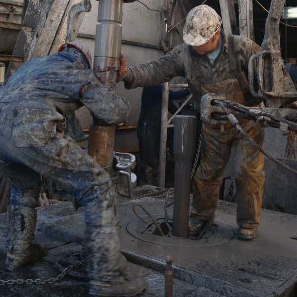 Two oilfield workers working on drilling equipment