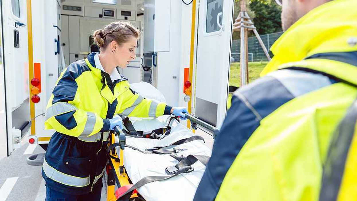 Two paramedics preparing a gurney outside of their ambulance