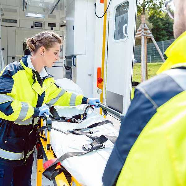 Two paramedics preparing a gurney outside of their ambulance