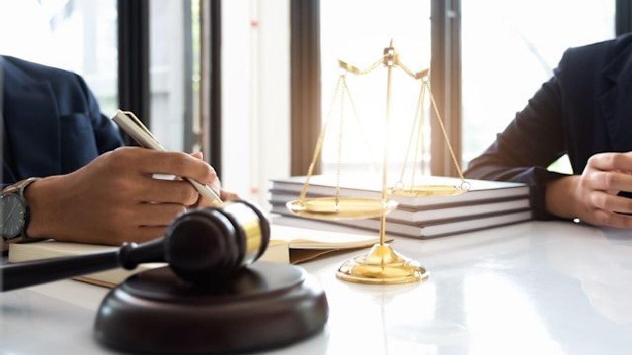 Two people at a desk with a judge's gavel and a model of the scales of justice