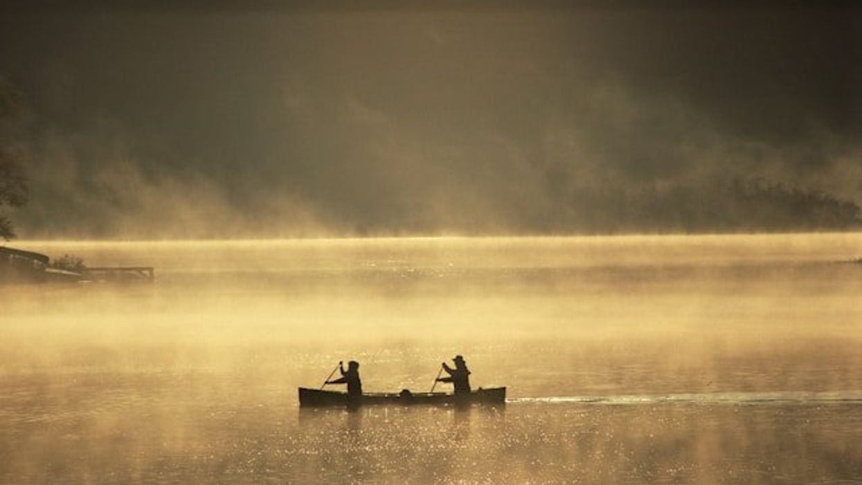 Two people in a canoe on a misty lake