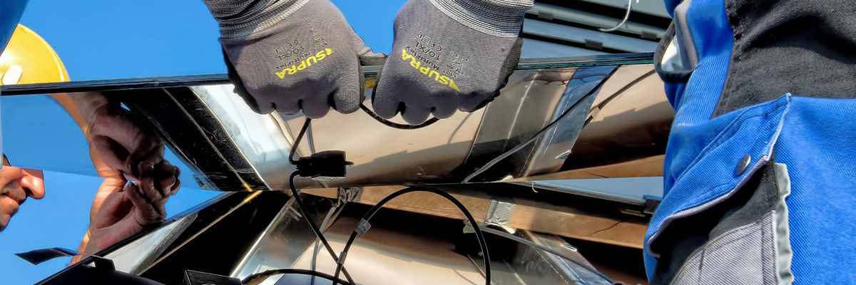 Two people installing a solar panel on a roof.
