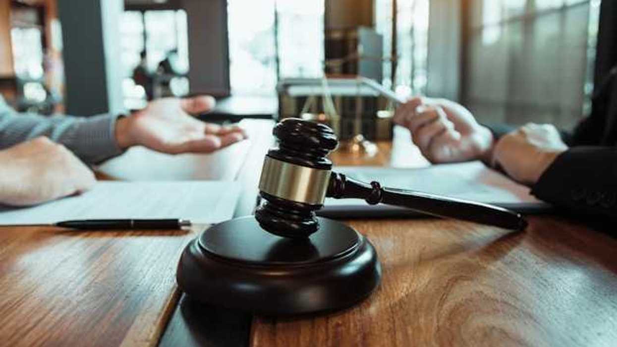 Two people sitting across from each other at a wooden table with a wooden gavel
