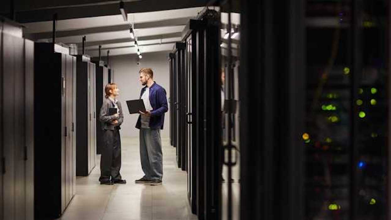 Two people standing and talking next to data servers in a data center