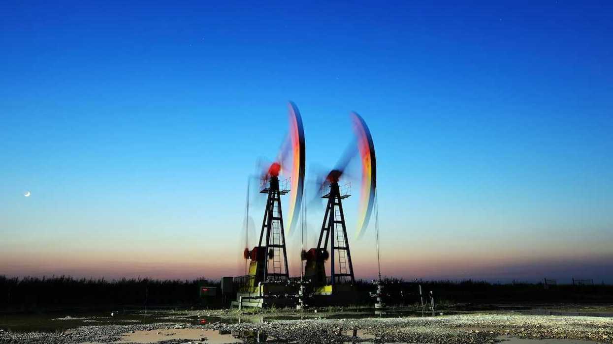 Two pumpjacks depicting blurred motion, surrounded by pools of standing water