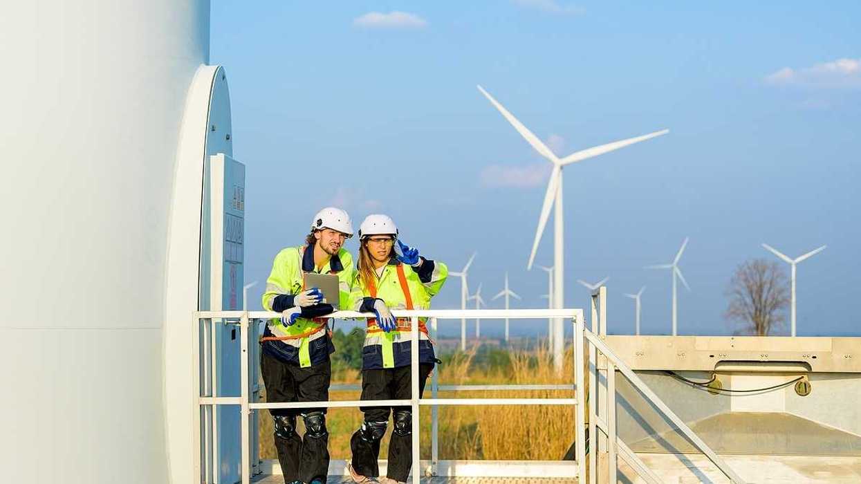 Two renewable energy engineers working on a wind turbine.