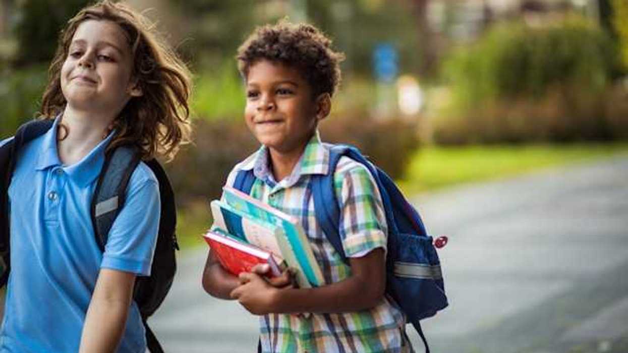 Two school children walking along a path toward school