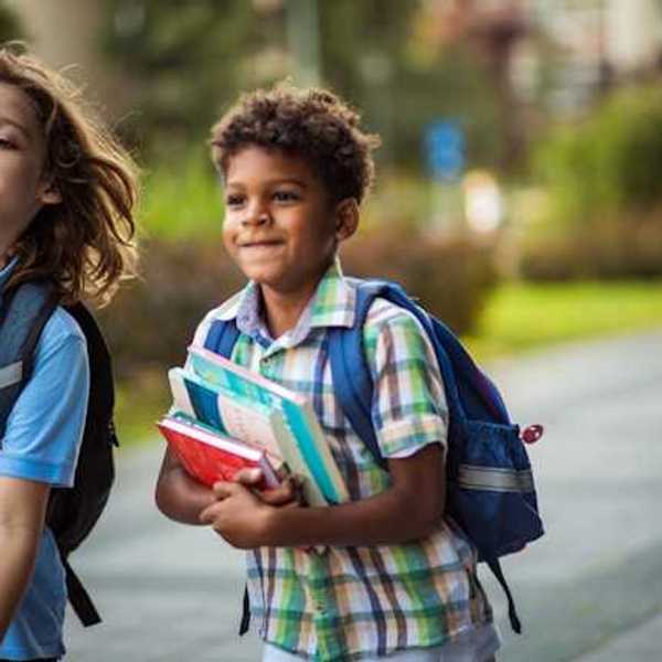 Two school children walking along a path toward school