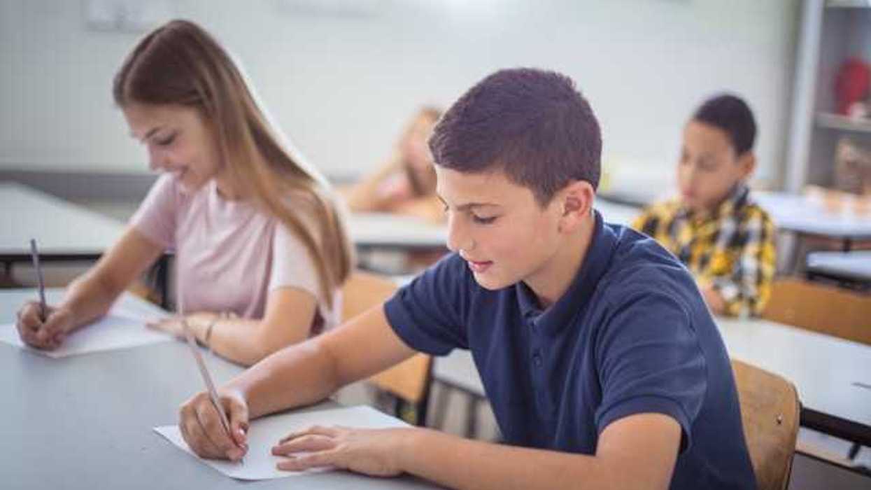 Two schoolchildren sitting at a desk in a classroom taking a test