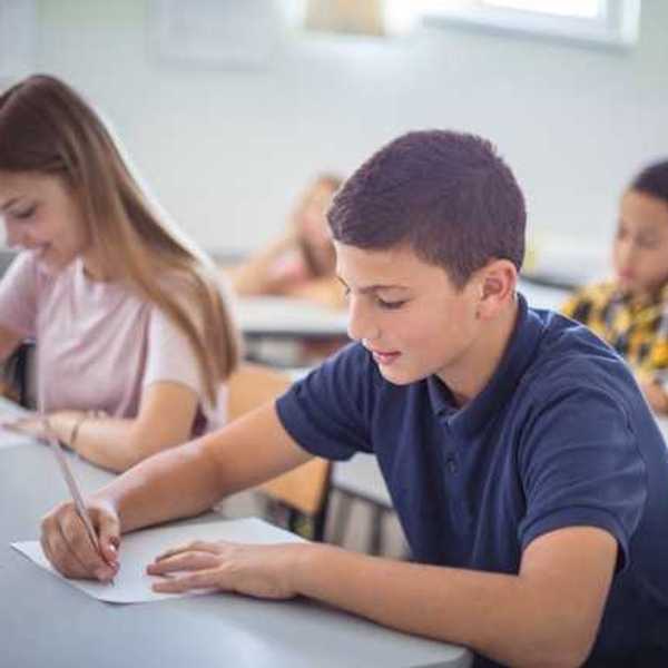 Two schoolchildren sitting at a desk in a classroom taking a test
