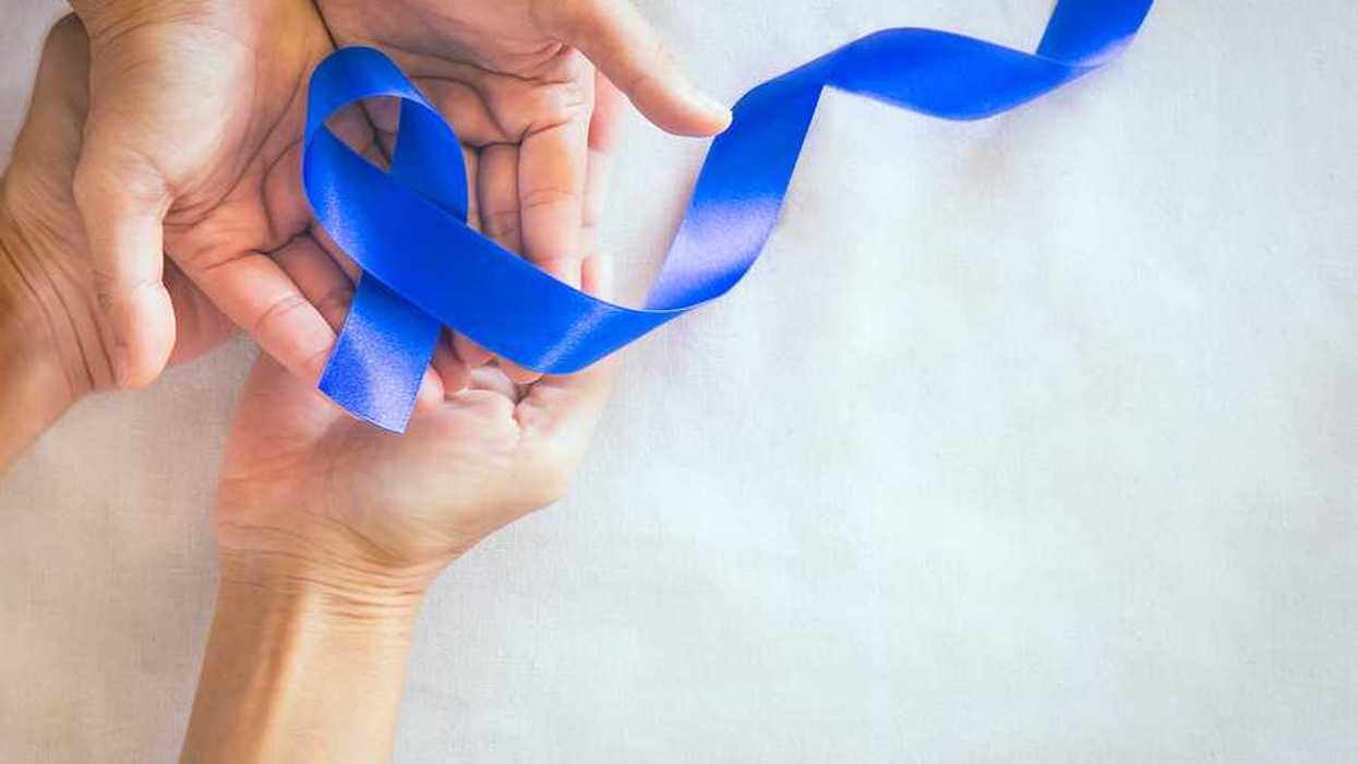 Two sets of hands holding a dark blue cancer awareness ribbon