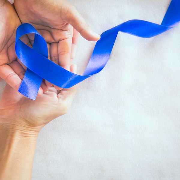 Two sets of hands holding a dark blue cancer awareness ribbon