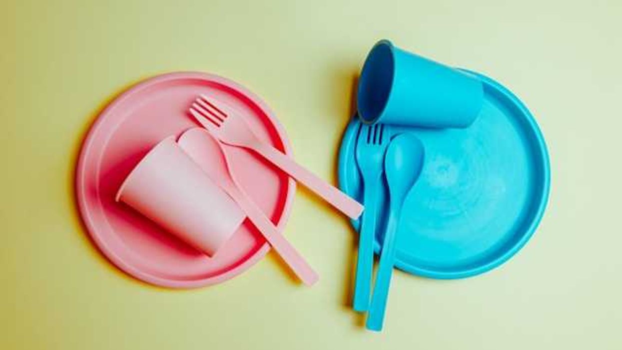 Two sets of plastic plates, cups and utensils against a light green background