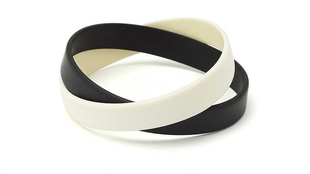 Two silicone wrist bands in black and white sitting on top of one another