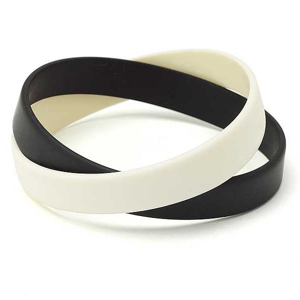 Two silicone wrist bands in black and white sitting on top of one another